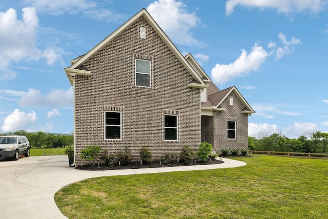 view of front of house featuring brick siding, fence, and a front yard