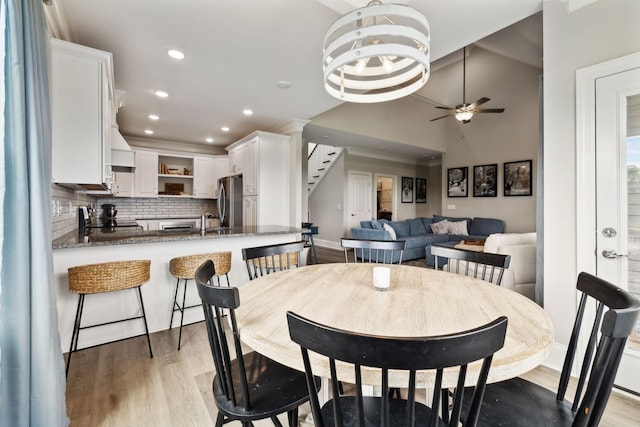 dining area featuring stairway, lofted ceiling, a ceiling fan, and light wood-style floors