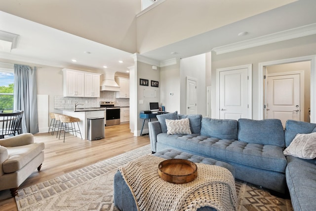 living room featuring crown molding, light wood-type flooring, and recessed lighting
