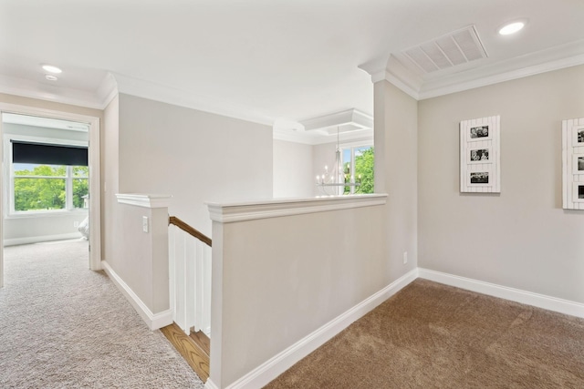 corridor with crown molding, carpet flooring, visible vents, and a chandelier