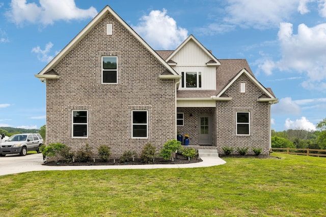 craftsman-style house with fence, brick siding, a front yard, board and batten siding, and a shingled roof