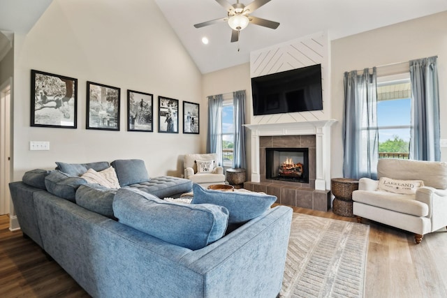 living room featuring a healthy amount of sunlight, ceiling fan, a tiled fireplace, and wood finished floors