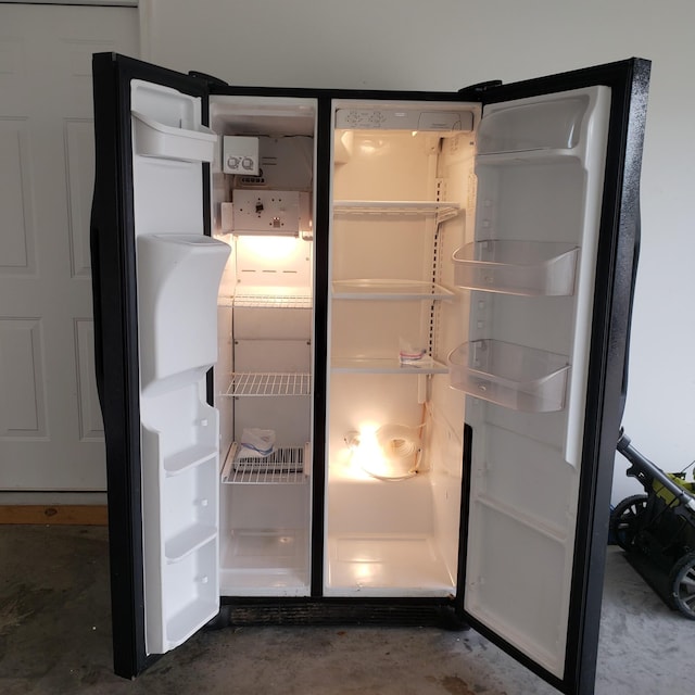 interior details featuring freestanding refrigerator and unfinished concrete flooring