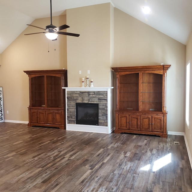 unfurnished living room featuring lofted ceiling, baseboards, a stone fireplace, ceiling fan, and wood finished floors