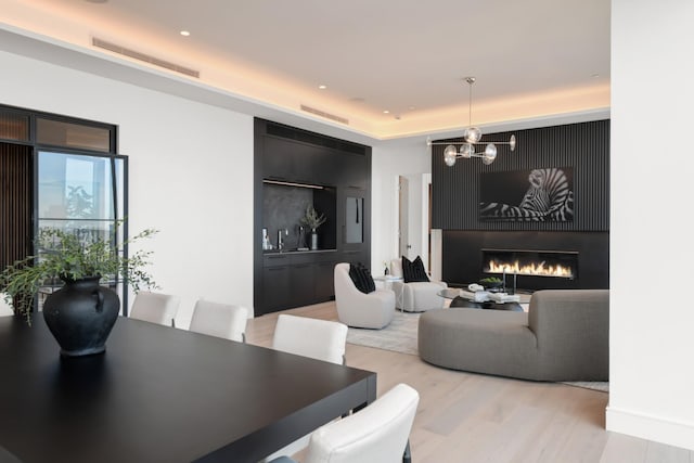 1616 W End Ave Unit 3202, Nashville, TN 37203 - dining area featuring a tray ceiling, a notable chandelier, light wood-type flooring, visible vents, and a warm lit fireplace