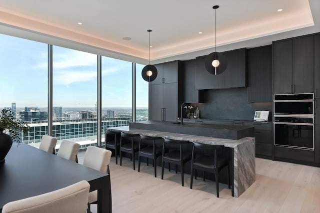 1616 W End Ave Unit 3202, Nashville, TN 37203 - kitchen featuring a sink, a kitchen breakfast bar, an island with sink, light wood finished floors, and modern cabinets
