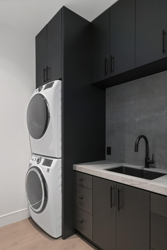 1616 W End Ave Unit 3202, Nashville, TN 37203 - laundry area featuring baseboards, a sink, stacked washer and dryer, light wood-style floors, and cabinet space
