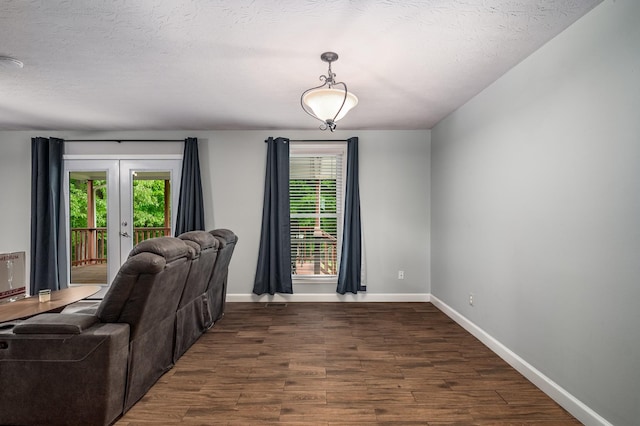 living area featuring a textured ceiling, baseboards, french doors, and dark wood finished floors