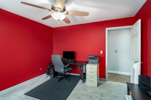 carpeted office with ceiling fan and baseboards
