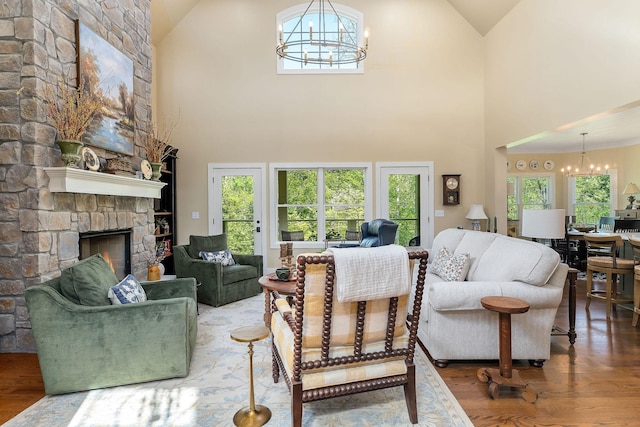 living room featuring wood finished floors, a chandelier, a fireplace, and high vaulted ceiling