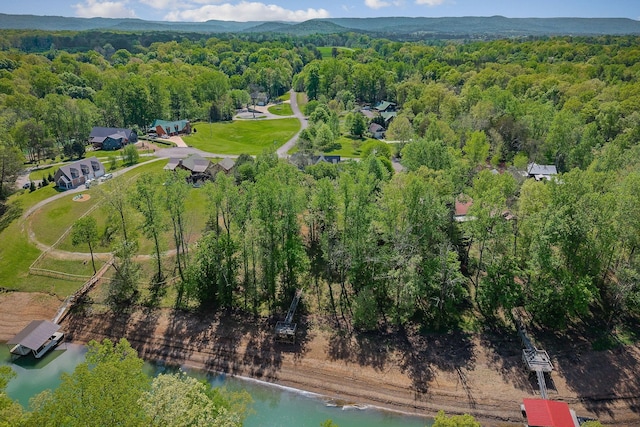 drone / aerial view with a water view and a forest view