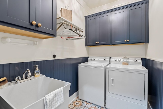 clothes washing area with washing machine and clothes dryer, wainscoting, cabinet space, and a sink