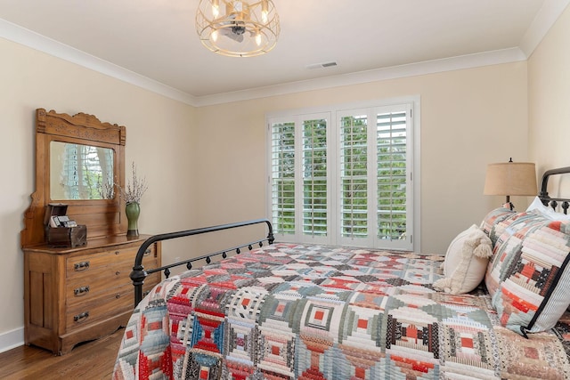 bedroom with crown molding, visible vents, and wood finished floors