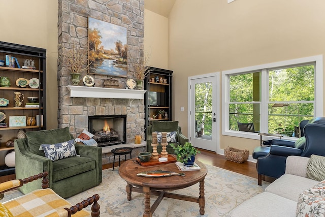 living room featuring baseboards, a fireplace, high vaulted ceiling, and wood finished floors