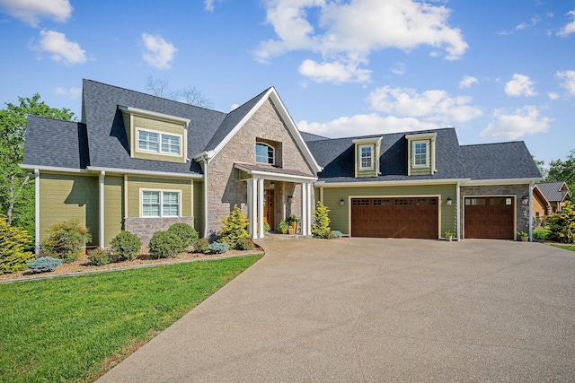 craftsman house featuring driveway, a front yard, an attached garage, a shingled roof, and stone siding