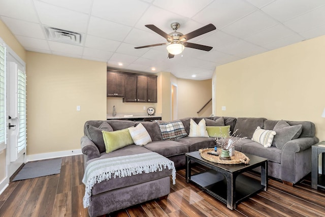living room featuring a ceiling fan, a paneled ceiling, visible vents, baseboards, and dark wood-style flooring