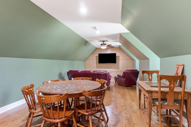 dining room featuring a ceiling fan, baseboards, visible vents, vaulted ceiling, and light wood-style floors