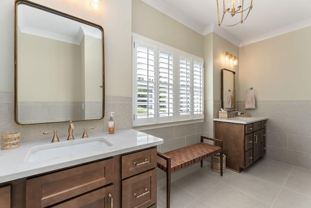 bathroom with a sink, two vanities, tile patterned floors, tile walls, and wainscoting