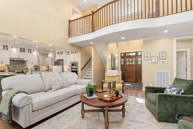 living area featuring visible vents, recessed lighting, stairway, a high ceiling, and light wood-style floors