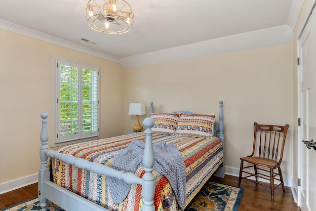 bedroom with baseboards, an inviting chandelier, visible vents, and wood finished floors