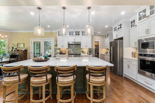 kitchen featuring under cabinet range hood, dark wood-type flooring, backsplash, light countertops, and appliances with stainless steel finishes