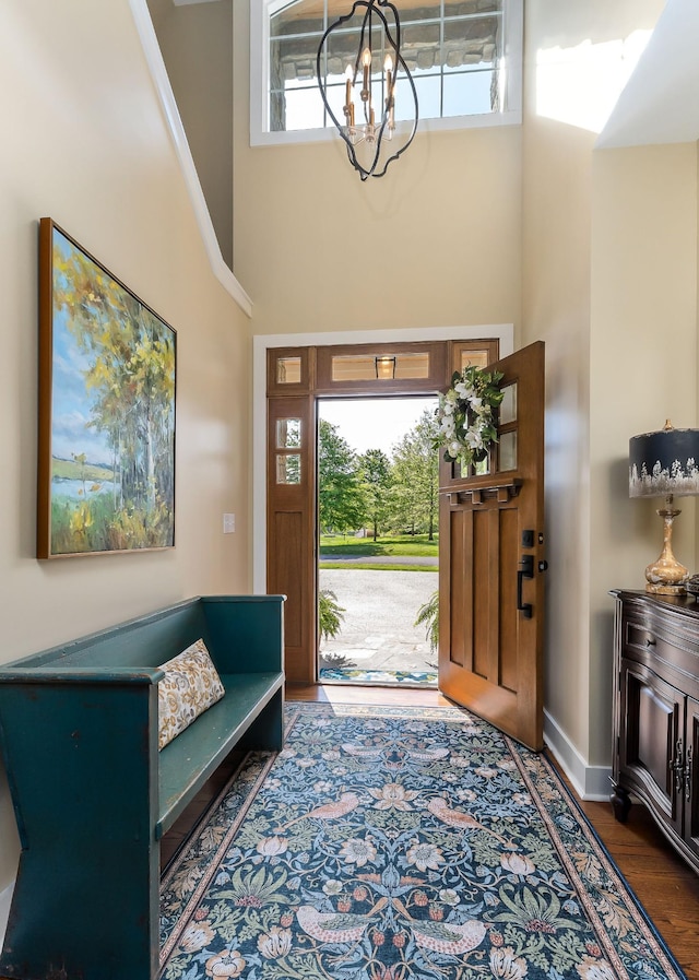 entryway with a chandelier, a high ceiling, a healthy amount of sunlight, and wood finished floors
