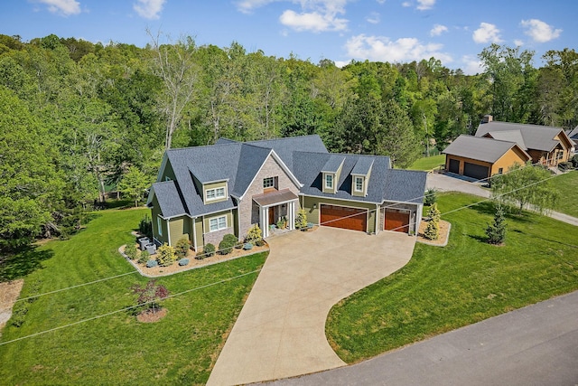 view of front of property with driveway, a view of trees, a front yard, and an attached garage