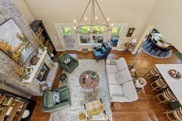 living area featuring a chandelier, a lit fireplace, wood finished floors, and baseboards