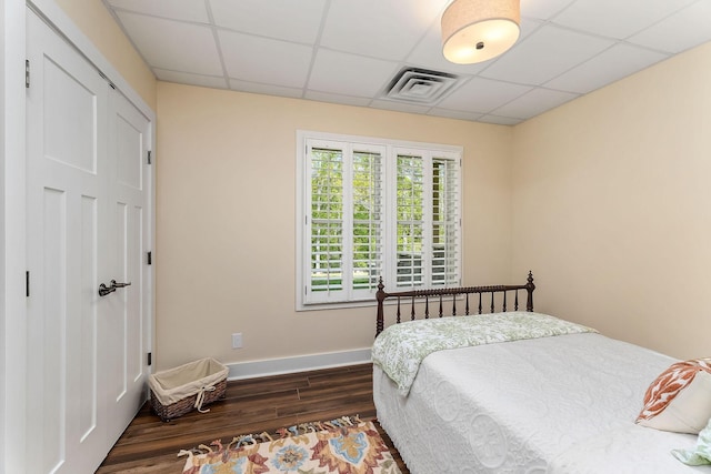 bedroom with baseboards, dark wood-style flooring, a drop ceiling, and visible vents