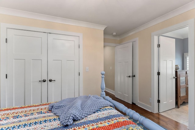 bedroom with baseboards, a closet, crown molding, and wood finished floors