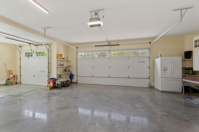 garage featuring white refrigerator with ice dispenser and a garage door opener