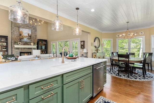 kitchen with hanging light fixtures, a sink, stainless steel dishwasher, dark wood-type flooring, and green cabinets