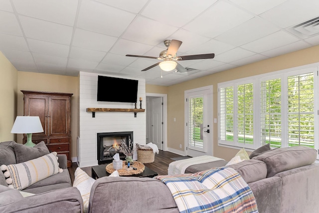 living room featuring a fireplace, a ceiling fan, visible vents, and wood finished floors