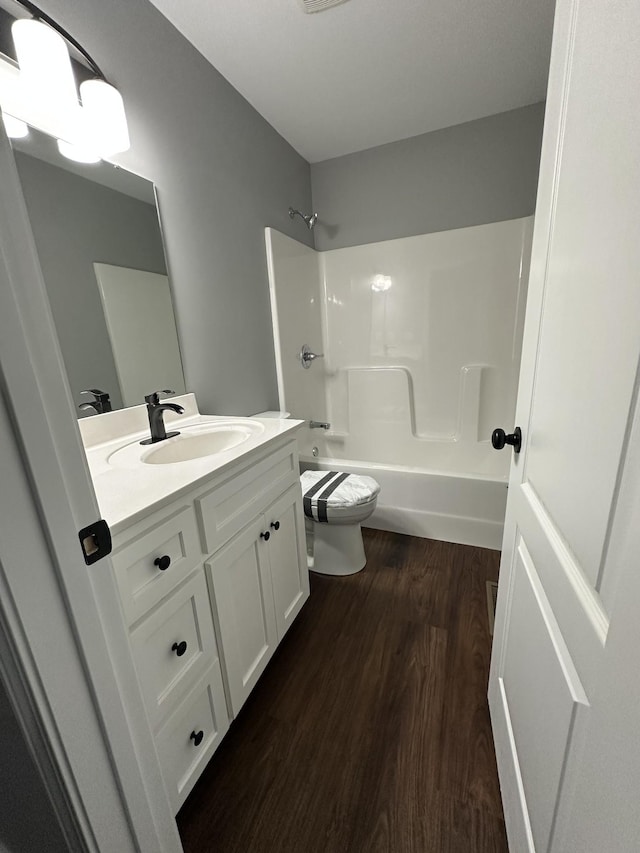 full bath featuring vanity, wood finished floors, shower / bath combination, and toilet