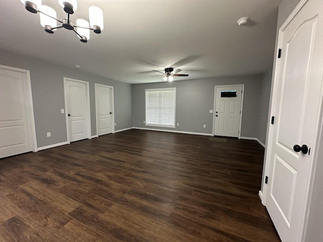 interior space with baseboards, ceiling fan with notable chandelier, and dark wood-style floors