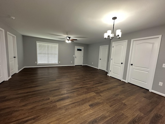 unfurnished dining area featuring baseboards, dark wood-style flooring, and ceiling fan with notable chandelier