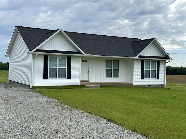 ranch-style home with board and batten siding, a shingled roof, and a front yard
