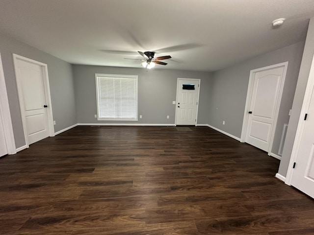 empty room with baseboards, dark wood finished floors, and ceiling fan