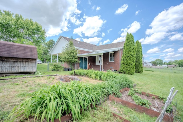 1876 Fall River Rd, Lawrenceburg, TN 38464 - view of front of home with a garden, brick siding, a storage unit, and an outdoor structure