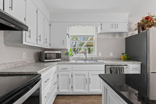 kitchen featuring a sink, under cabinet range hood, dark wood-style floors, white cabinets, and appliances with stainless steel finishes