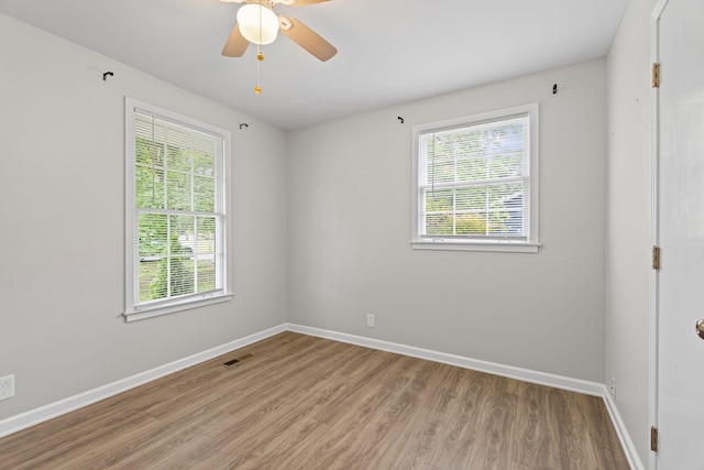 unfurnished room with baseboards, plenty of natural light, and wood finished floors