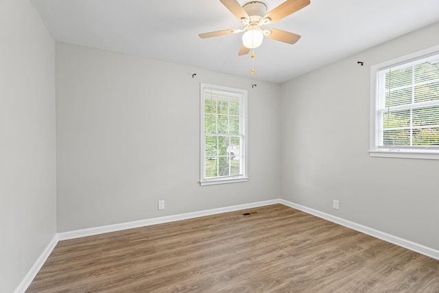 empty room featuring visible vents, baseboards, plenty of natural light, and wood finished floors