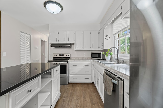 kitchen with a sink, stainless steel appliances, under cabinet range hood, dark wood-style floors, and white cabinets