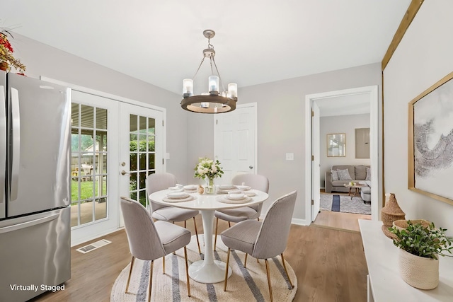 dining room featuring wood finished floors, french doors, a notable chandelier, visible vents, and baseboards