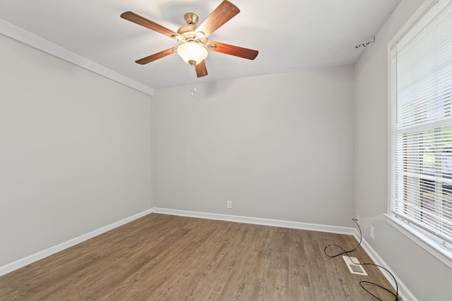 empty room featuring baseboards, visible vents, a ceiling fan, and wood finished floors