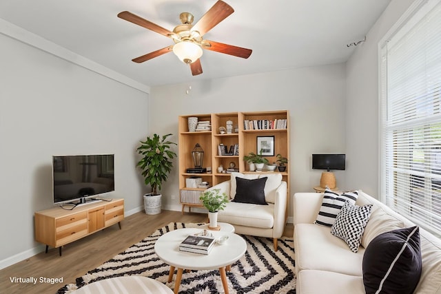 living area featuring light wood finished floors, baseboards, and a ceiling fan