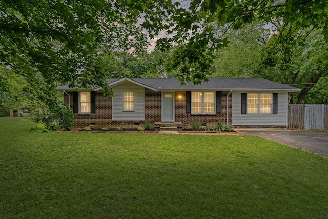 ranch-style home featuring aphalt driveway, fence, brick siding, crawl space, and a front yard
