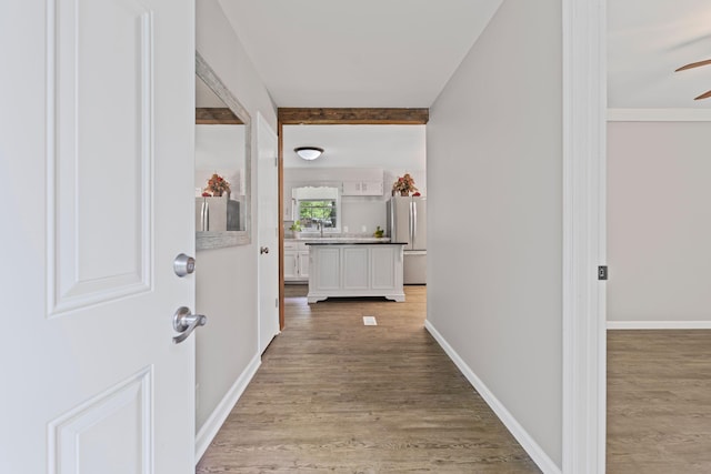 corridor with light wood-type flooring and baseboards