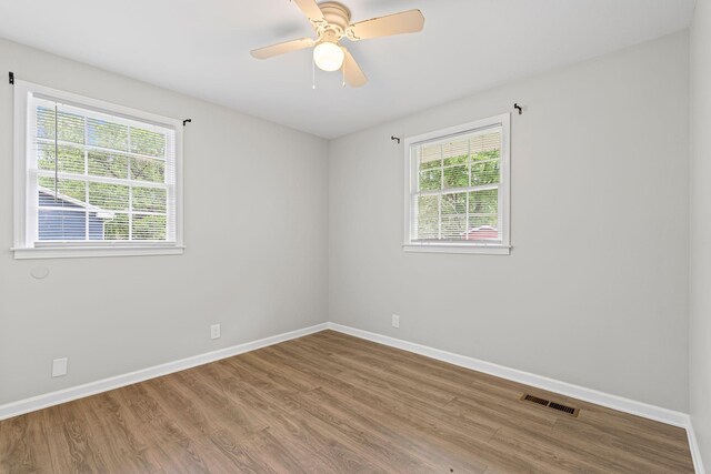 empty room with wood finished floors, visible vents, baseboards, and ceiling fan