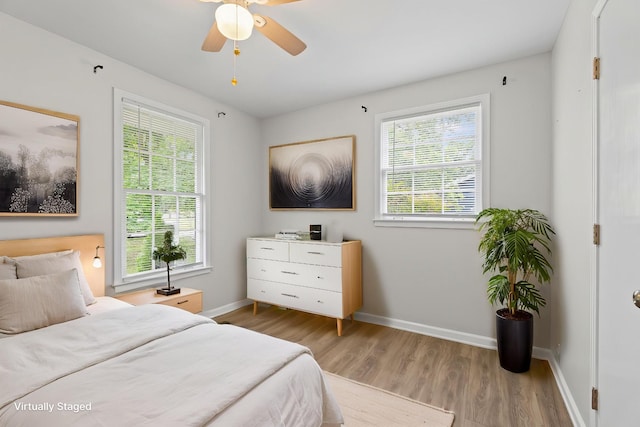 bedroom featuring baseboards, a ceiling fan, multiple windows, and wood finished floors